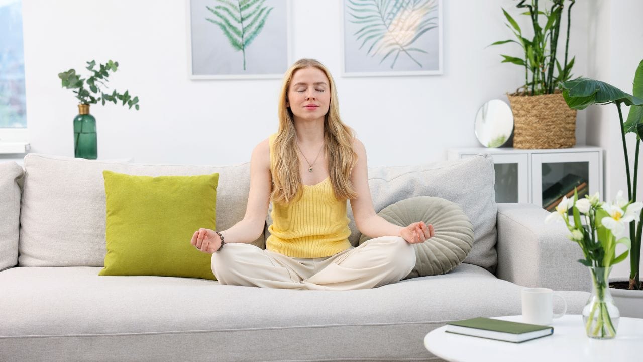 woman sitting on sofa doing Open Monitoring Meditation
