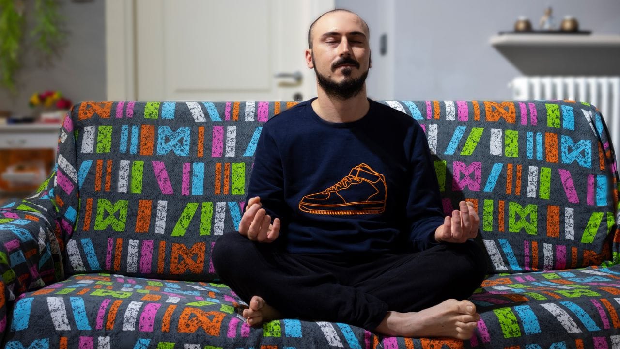 man sitting on sofa doing compassion meditation