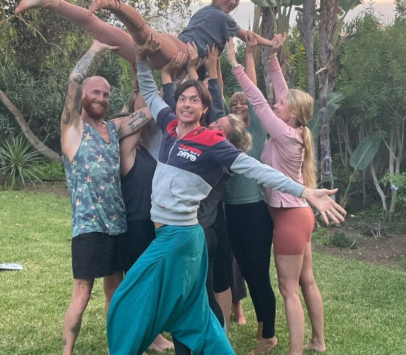 group of students lifting another student in the air in garden